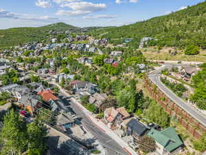 Aerial view of residential area featuring a mountainous background and a heavily wooded area