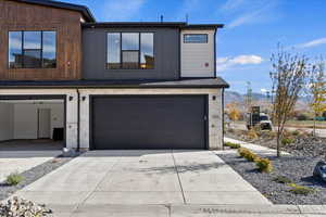 Modern home featuring stone siding, driveway, a garage, and a mountain view