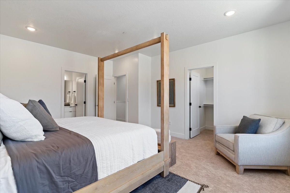 Carpeted bedroom with a walk in closet, ensuite bath, and recessed lighting