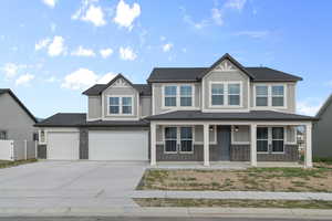 Craftsman-style home featuring board and batten siding, concrete driveway, covered porch, and brick siding