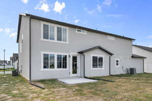 Back of property featuring stucco siding, a patio, and a yard