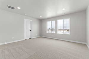 Empty room with light carpet and recessed lighting