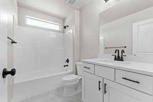 Full bath with vanity, marble look tiles, and  shower combination