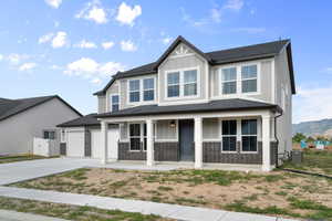 View of front of house with board and batten siding, covered porch, driveway, an attached garage, and a mountain view