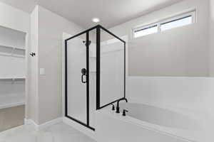 Bathroom with a garden tub, a shower stall, a spacious closet, and marble look tile flooring