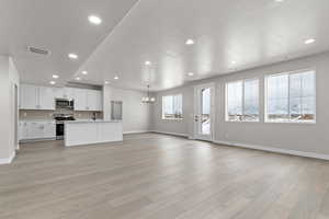 Unfurnished living room featuring a chandelier, recessed lighting, and light wood-type flooring