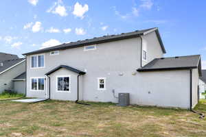 Rear view of property with stucco siding, a yard, and a patio