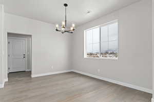 Empty room with a chandelier and light wood finished floors