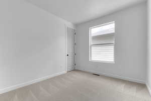 Spare room featuring light colored carpet and baseboards