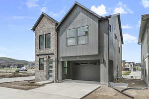 Contemporary house with a garage, concrete driveway, and brick siding
