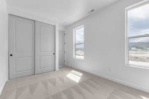 Unfurnished bedroom with light carpet and a closet