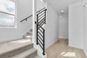 Stairs with wood finished floors, plenty of natural light, and recessed lighting