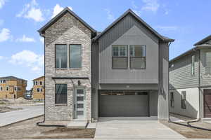 Contemporary house featuring brick siding, driveway, and a garage