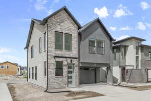 View of front of house featuring a garage, brick siding, driveway, and stucco siding