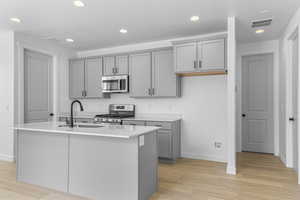 Kitchen featuring stainless steel appliances, gray cabinetry, light wood finished floors, a kitchen island with sink, and recessed lighting
