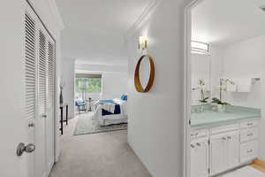 Hallway with light carpet, crown molding, and a textured ceiling