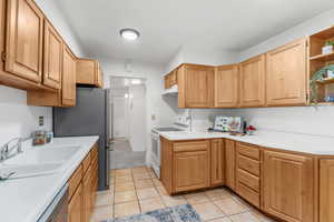 Kitchen with stainless steel appliances, under cabinet range hood, light countertops, and open shelves