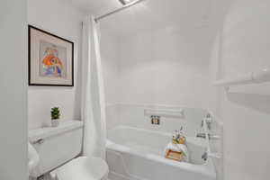Bathroom featuring toilet and shower / bath combo with shower curtain