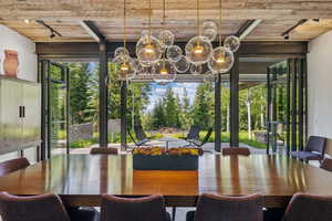 Dining space featuring track lighting and a wooden ceiling with exposed beams