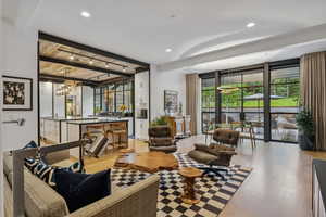 Living room with beam ceiling, light wood finished floors, recessed lighting, and a chandelier