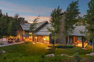 Rear view of property with a standing seam roof, a chimney, and a metal roof