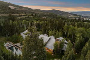 Aerial overview of property's location featuring mountains and a forest
