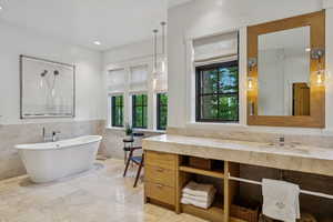 Bathroom featuring tile walls, a soaking tub, vanity, wainscoting, and marble finish flooring