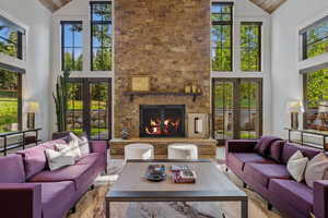 Living room featuring french doors, high vaulted ceiling, plenty of natural light, and a fireplace