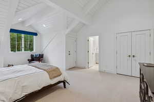 Bedroom with light colored carpet, wood ceiling, and ensuite bathroom