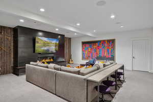 Living area featuring light colored carpet, recessed lighting, beam ceiling, and a glass covered fireplace