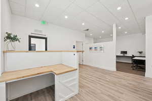 Unfurnished office with light wood-style flooring, recessed lighting, built in desk, and a paneled ceiling