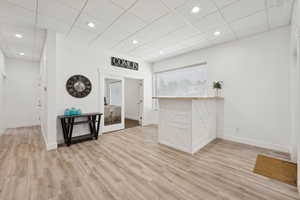 Empty room with light wood-type flooring, a drop ceiling, and recessed lighting
