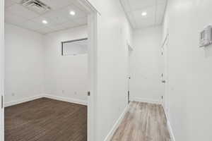 Hallway with a drop ceiling, wood finished floors, and recessed lighting