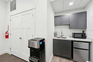 Indoor wet bar featuring freestanding refrigerator, black microwave, and a paneled ceiling