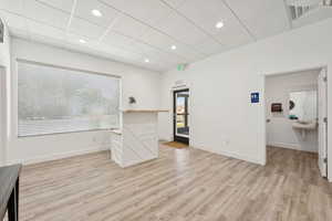 Unfurnished living room featuring light wood-style flooring, healthy amount of natural light, a paneled ceiling, and recessed lighting