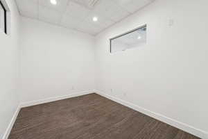 Empty room with a paneled ceiling, recessed lighting, and dark wood-style floors