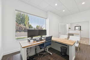 Home office featuring a paneled ceiling, recessed lighting, and dark wood-type flooring