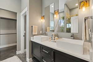 Full bath featuring double vanity, concrete floors, recessed lighting, and tiled shower