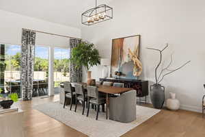 Dining area featuring a high ceiling, a chandelier, and wood finished floors