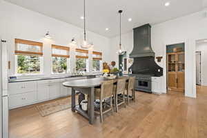 Kitchen featuring range with two ovens, custom range hood, light wood-style flooring, decorative light fixtures, and recessed lighting
