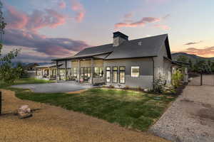 Rear view of property with stucco siding, a chimney, and a shingled roof