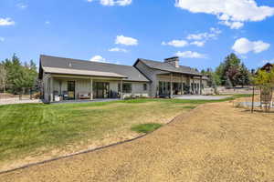 Rear view of property featuring board and batten siding, a chimney, and a patio