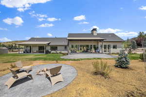 Back of property featuring a patio area, a chimney, and board and batten siding