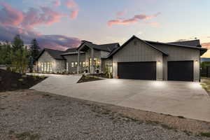 View of front of home with driveway, a garage, board and batten siding, and stone siding