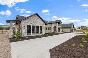 View of front of home with stone siding and driveway