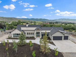 View of front of property with an attached garage, a mountain view, driveway, and a chimney