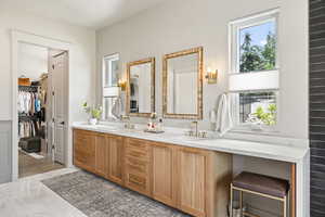 Bathroom featuring healthy amount of natural light, double vanity, and a walk in closet