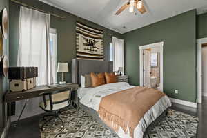 Bedroom featuring multiple windows, an office area, connected bathroom, and a ceiling fan