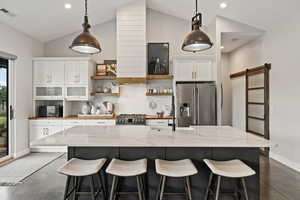Kitchen with stainless steel appliances, concrete flooring, open shelves, tasteful backsplash, and vaulted ceiling