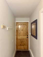Doorway with a textured ceiling, a textured wall, and a baseboard radiator